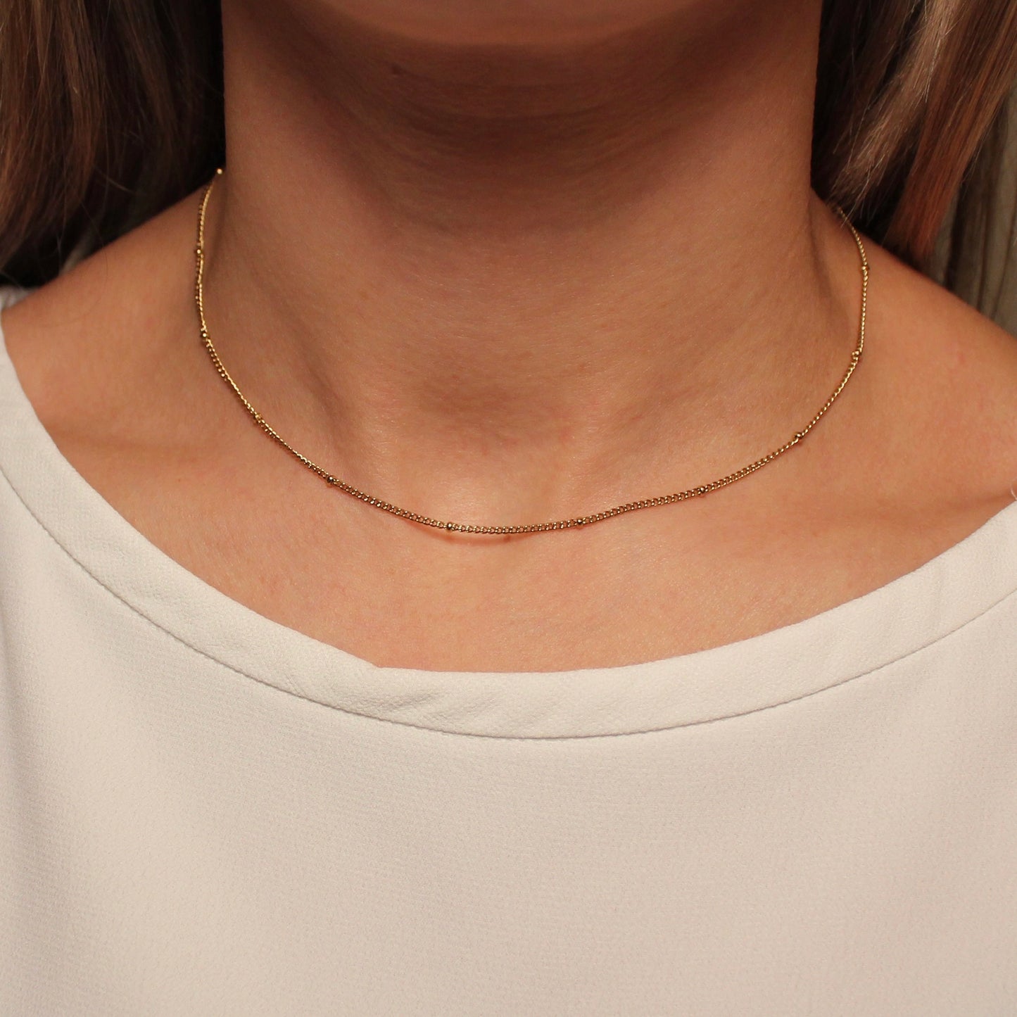 Gouden ketting met bolletjes die gedragen wordt