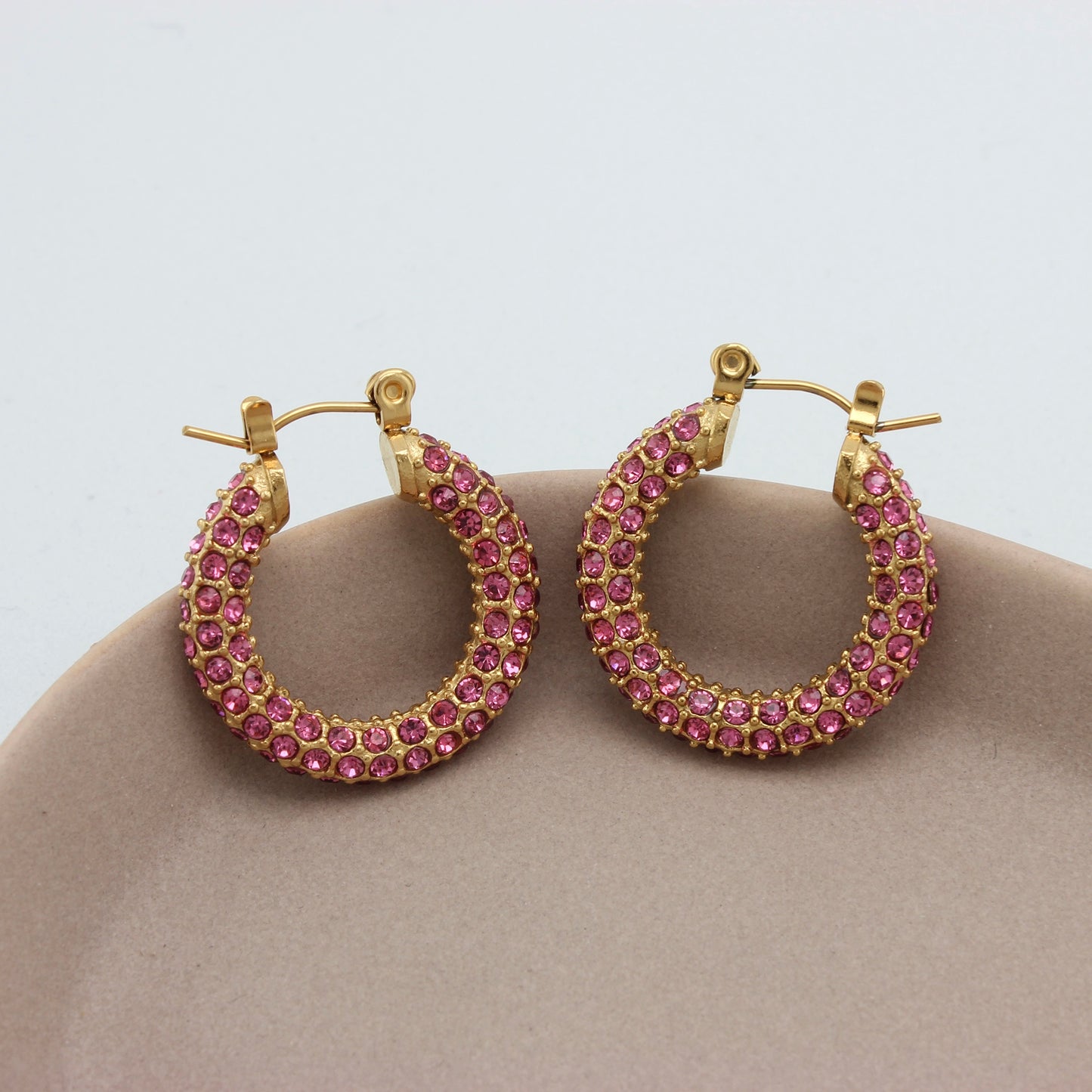 Gouden hoops met roze zirkonia steentjes op een schaaltje