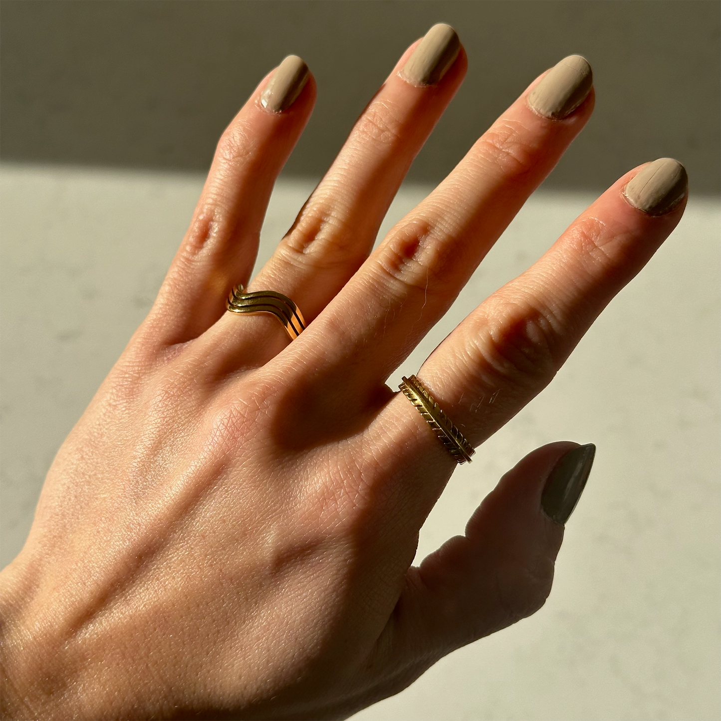 Gouden ring met drie boogjes en gouden ring aan hand