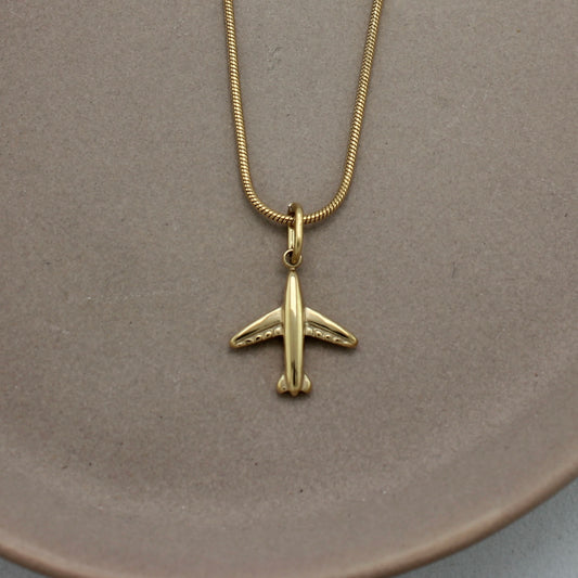 Ingezoomde foto van gouden ketting met gouden vliegtuigje als hanger