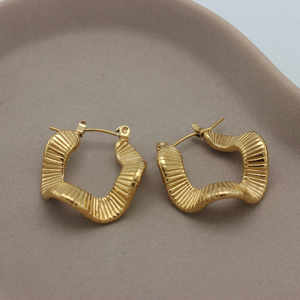 Gouden golvende oorbellen liggend op een schaaltje