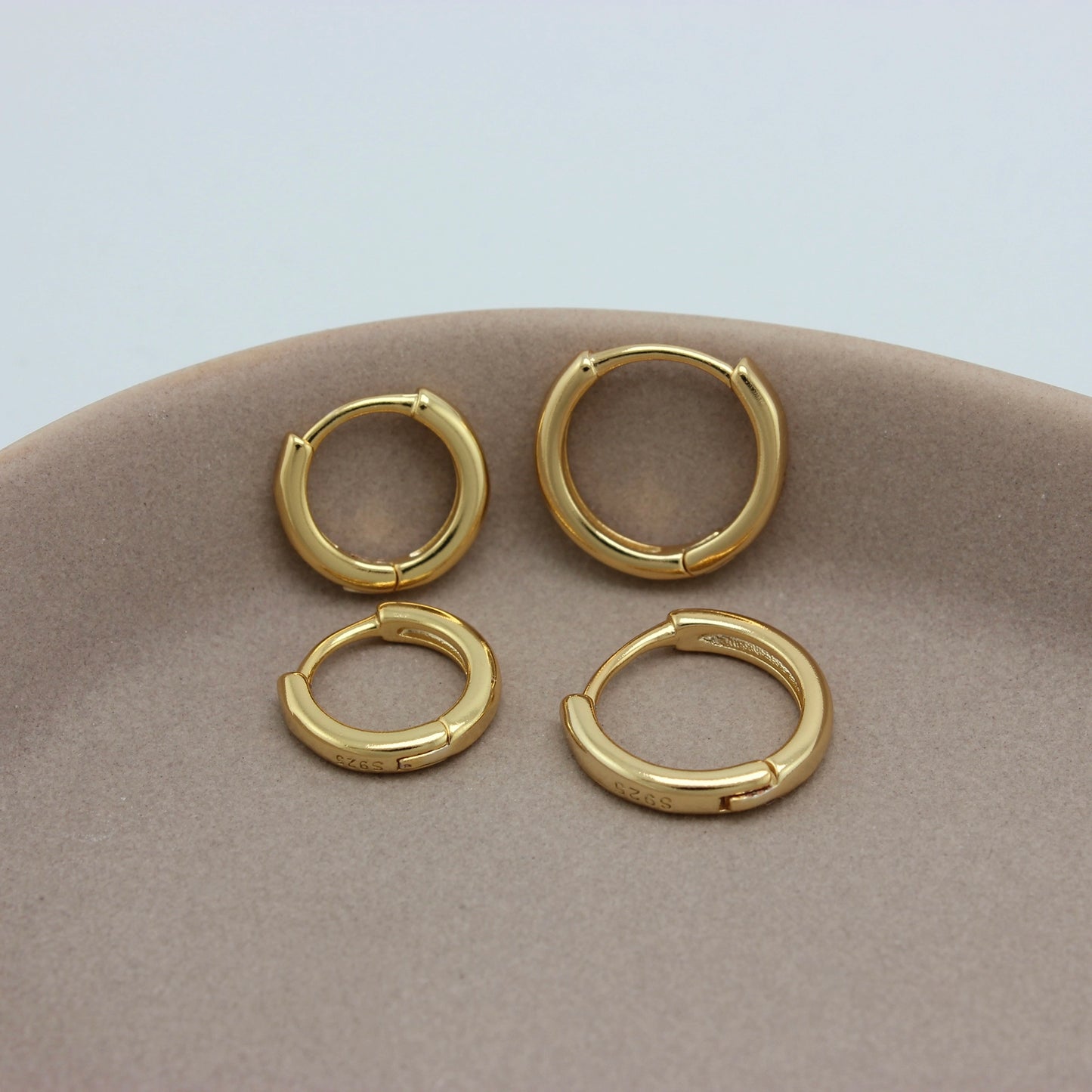 Kleine gouden hoops in twee formaten op een schaaltje