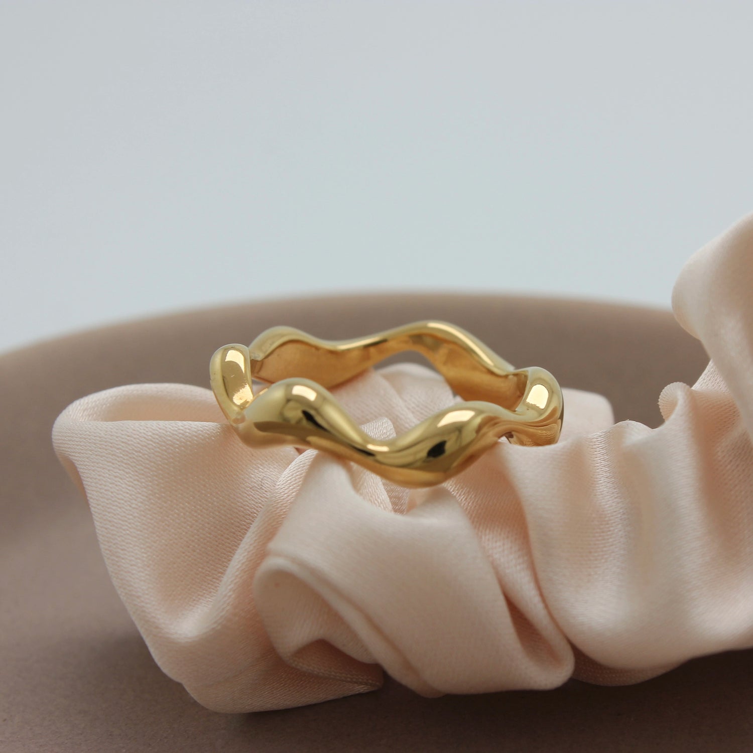 Een Asymmetrische gouden Ring Abby op een stuk stof
