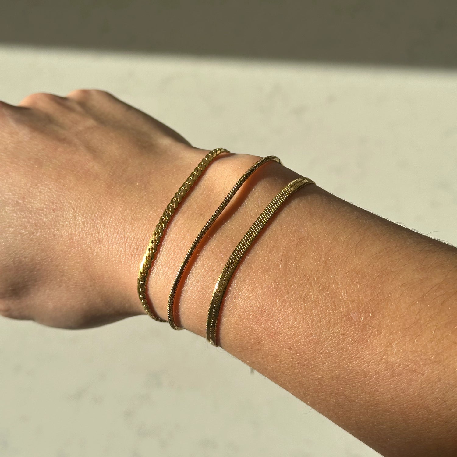 Drie gouden armbanden om een arm