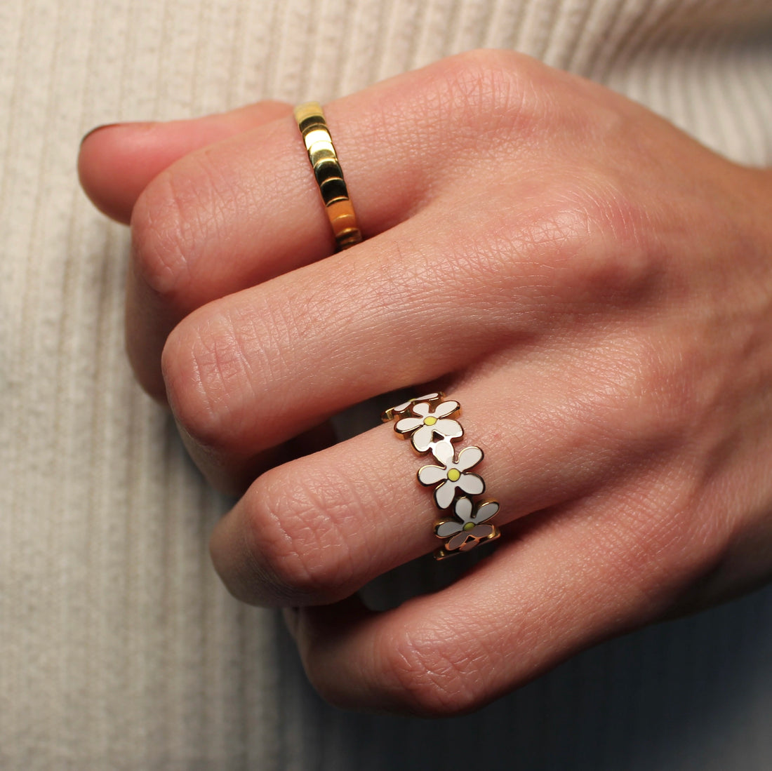 Een gedragen gouden ring met schubben en een ring met witte bloemen