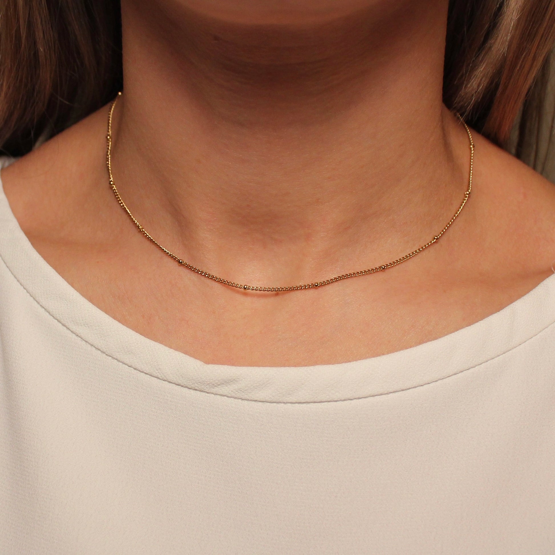 Gouden ketting met bolletjes die gedragen wordt