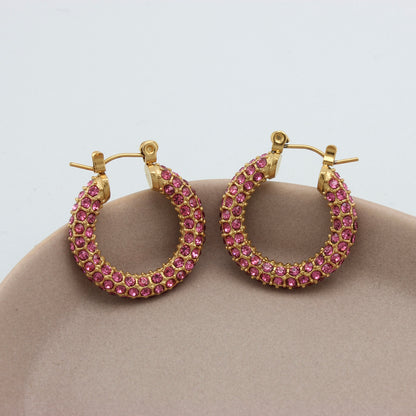 Gouden hoops met roze zirkonia steentjes op een schaaltje