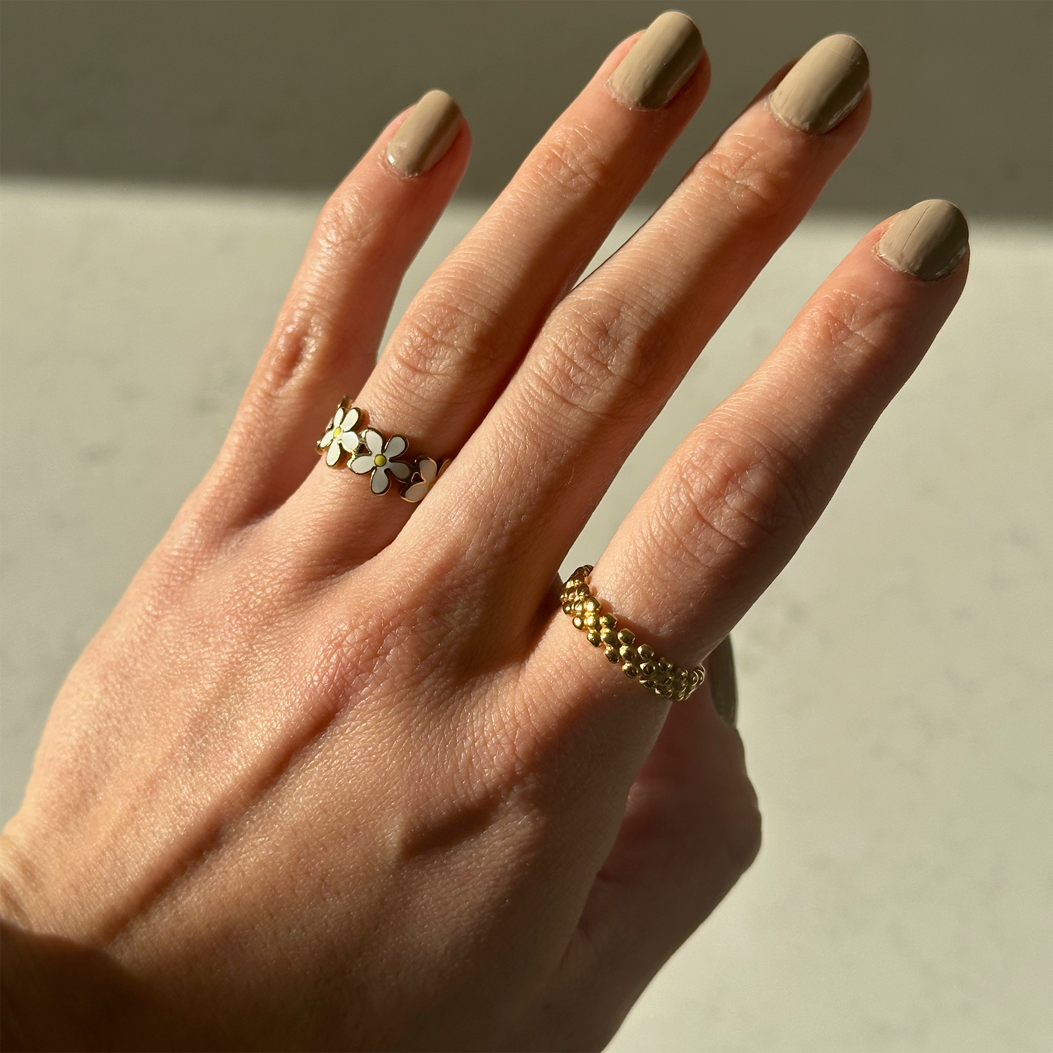 Een gouden bloemen ring en een gouden ring  op een hand