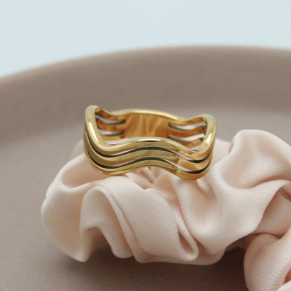 Gouden ring met boogjes op een beige stof