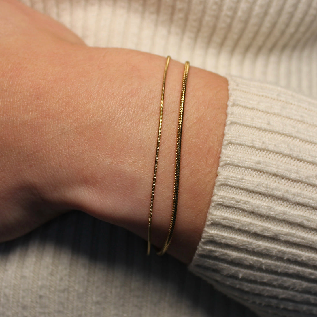 Een subtiele en grovere gouden armband om een pols