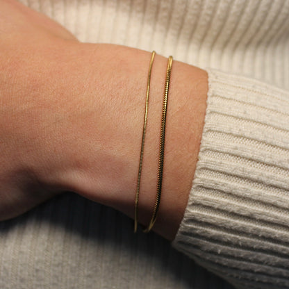 Een subtiele en grovere gouden armband om een pols