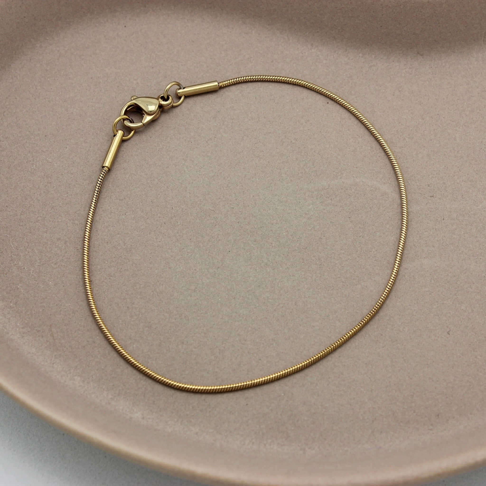 Bovenaanzicht van een minimalistische gouden armband met een erg fijne schakel