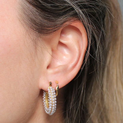Gouden oorbellen met parels in een oor