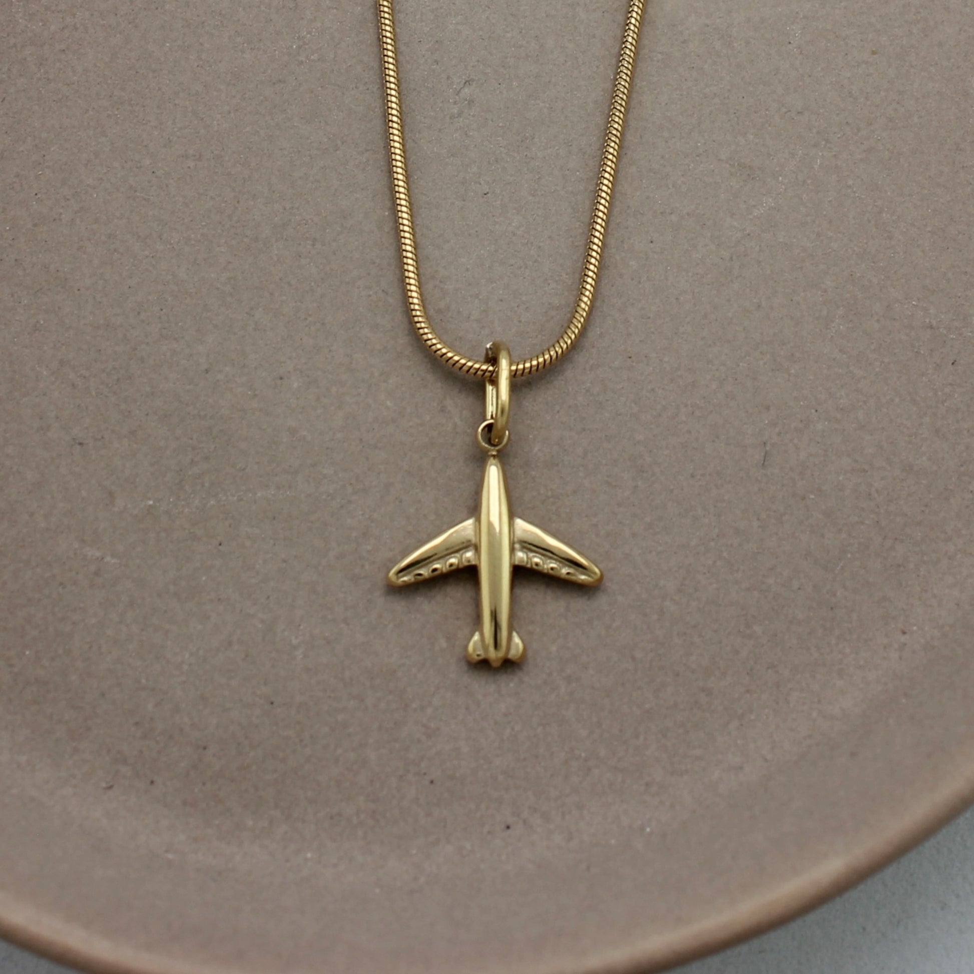 Ingezoomde foto van gouden ketting met gouden vliegtuigje als hanger