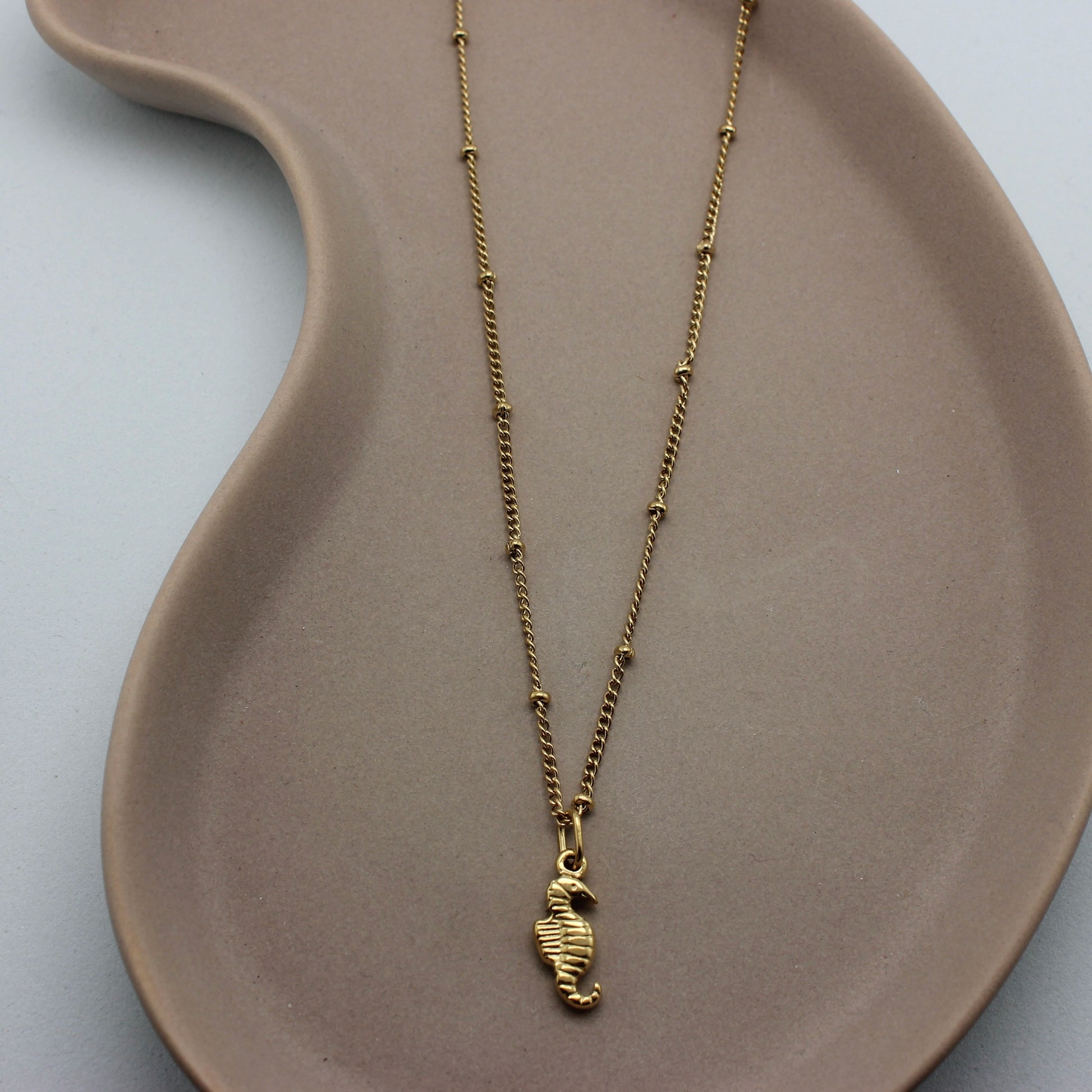 Gouden ketting met bolletjes en een gouden zeepaardje als hanger