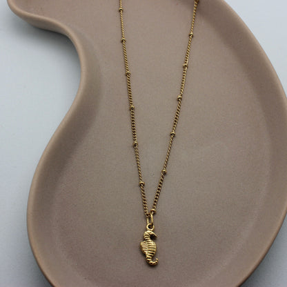 Gouden ketting met bolletjes en een gouden zeepaardje als hanger