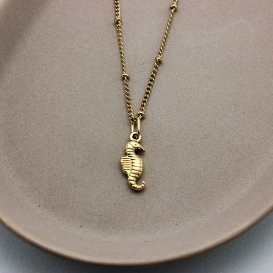 Gouden ketting met bolletjes en een gouden zeepaardje als hanger ingezoomd