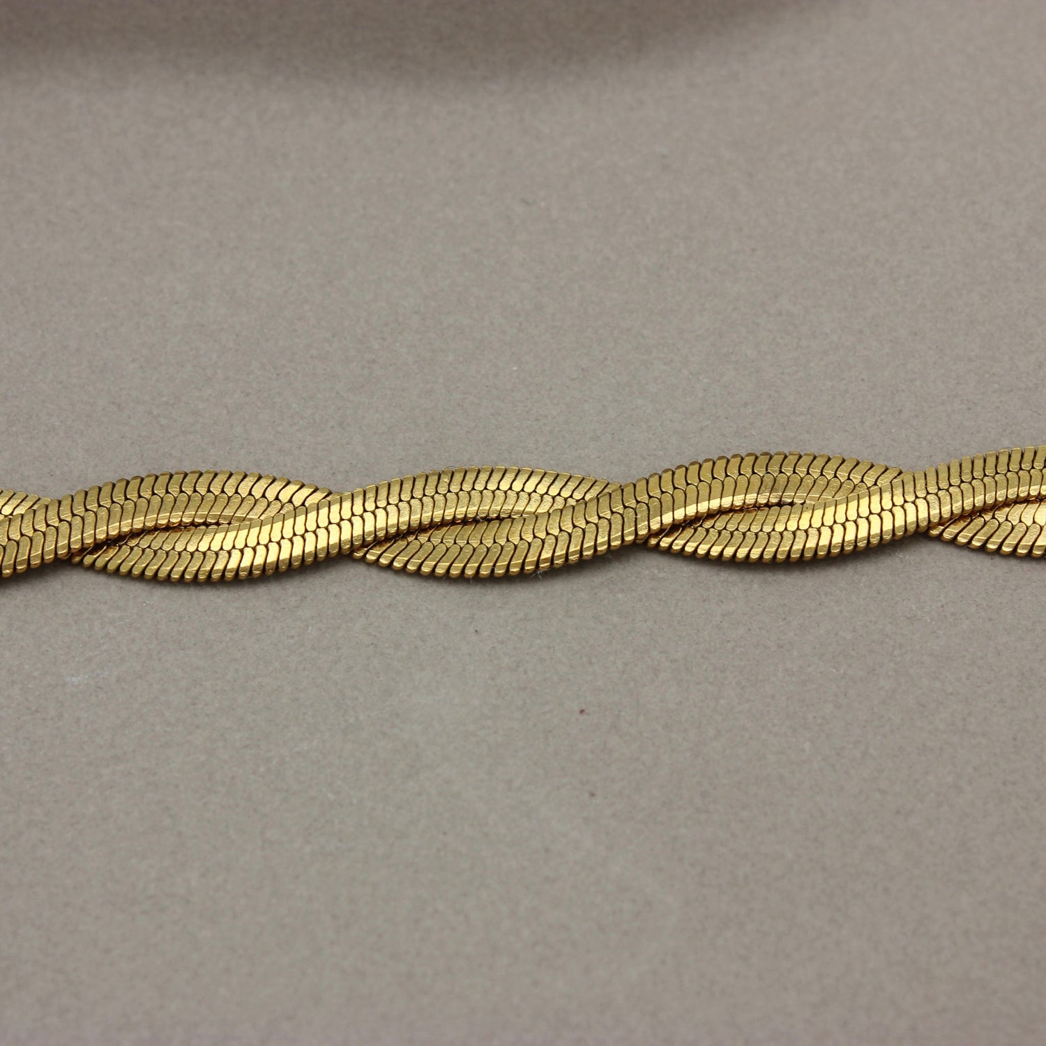 Detail van gevlochten platte gouden ketting