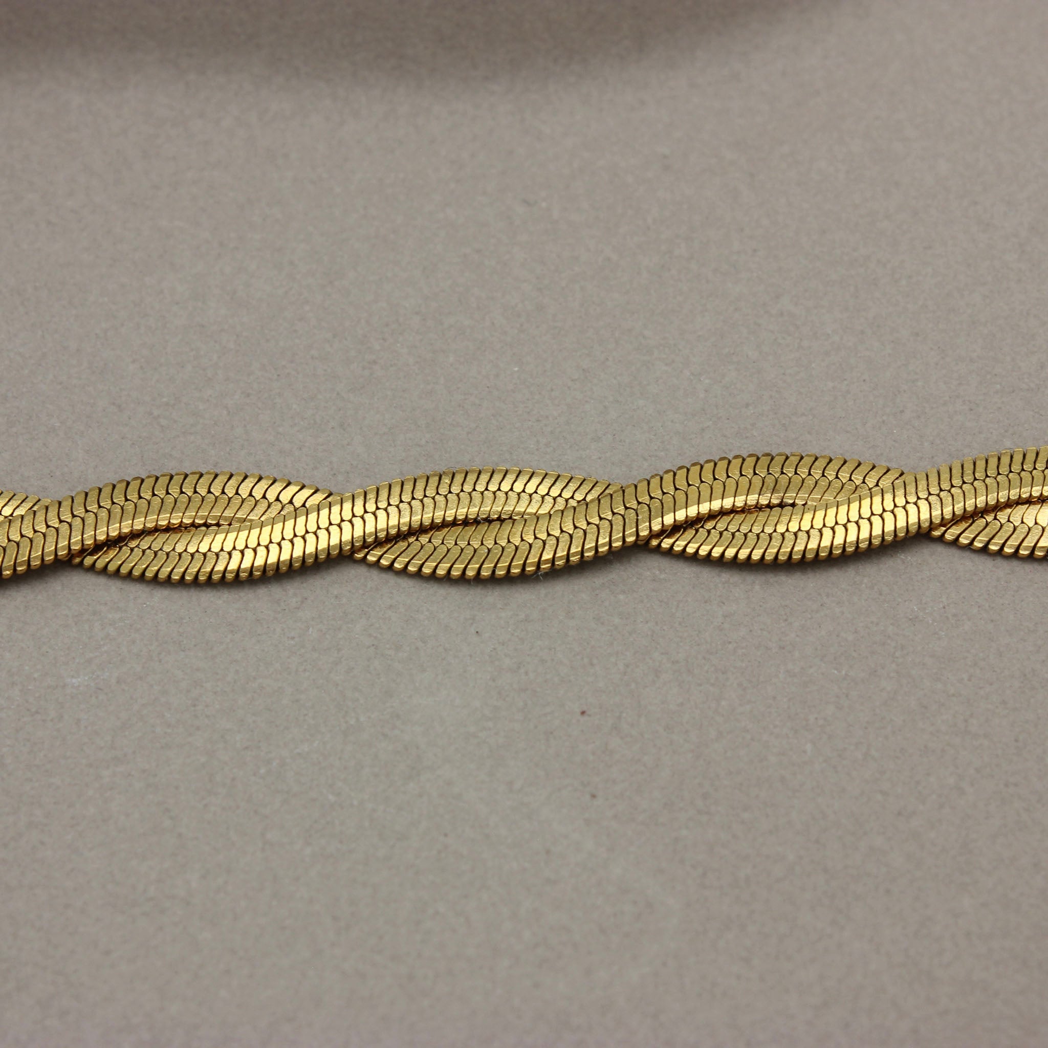 Detail van gevlochten platte gouden ketting