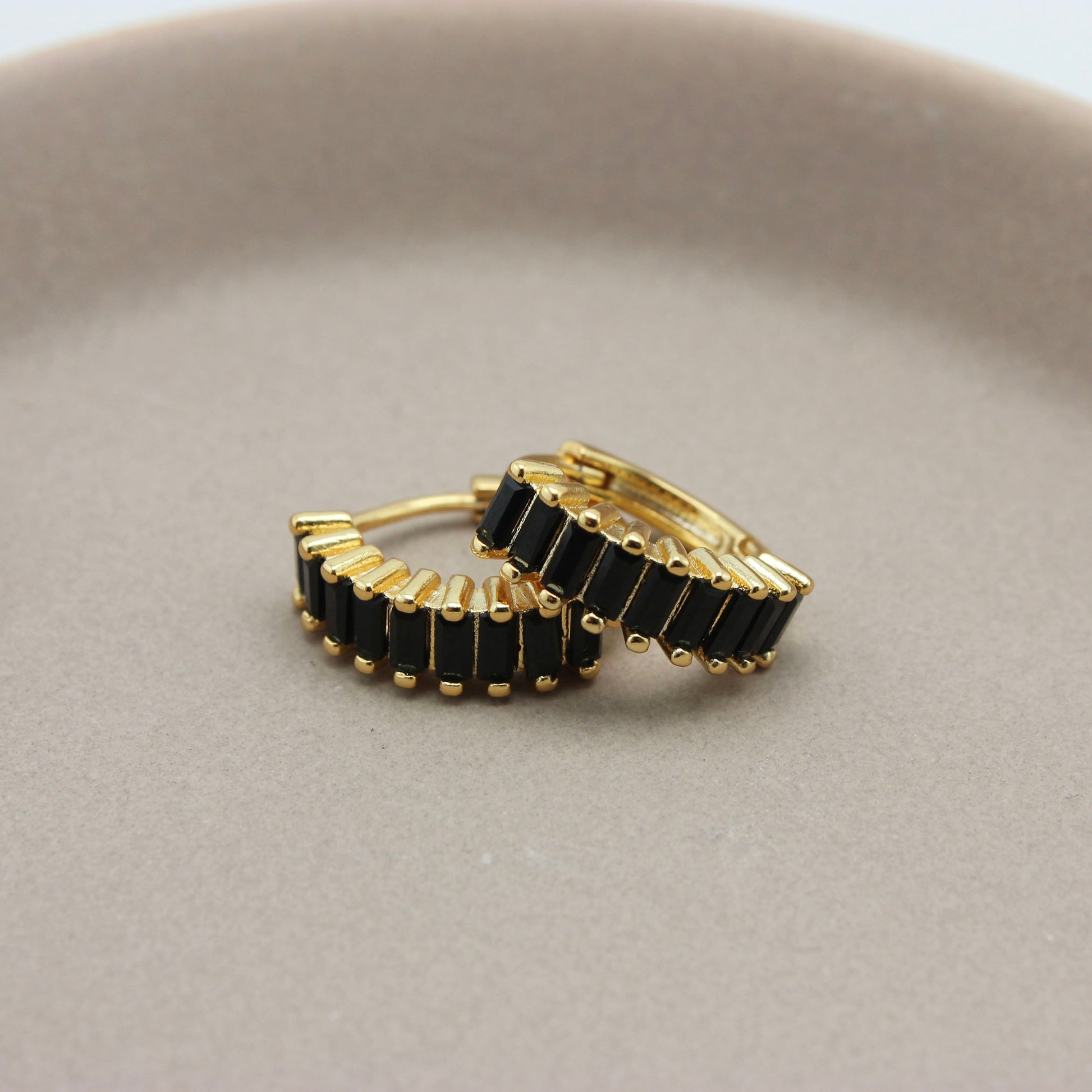 Gouden hoops met zwarte zirkonia steentjes liggend