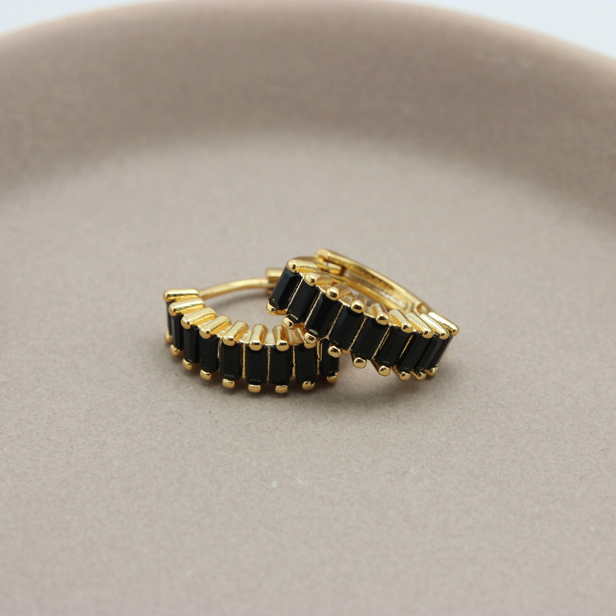 Gouden hoops met zwarte zirkonia steentjes liggend