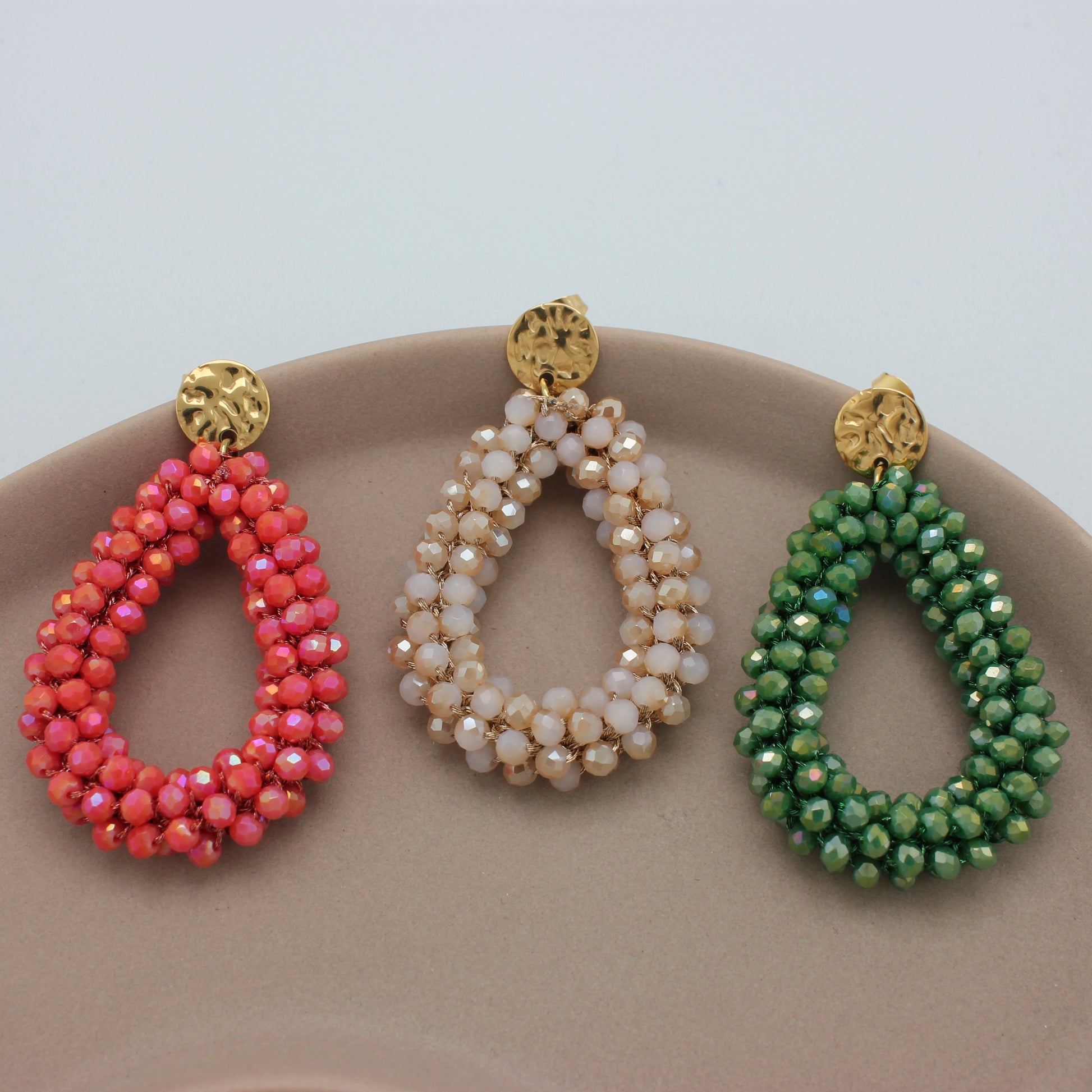 Drie gouden oorbellen met koraal, beige en groene kristallen kralen