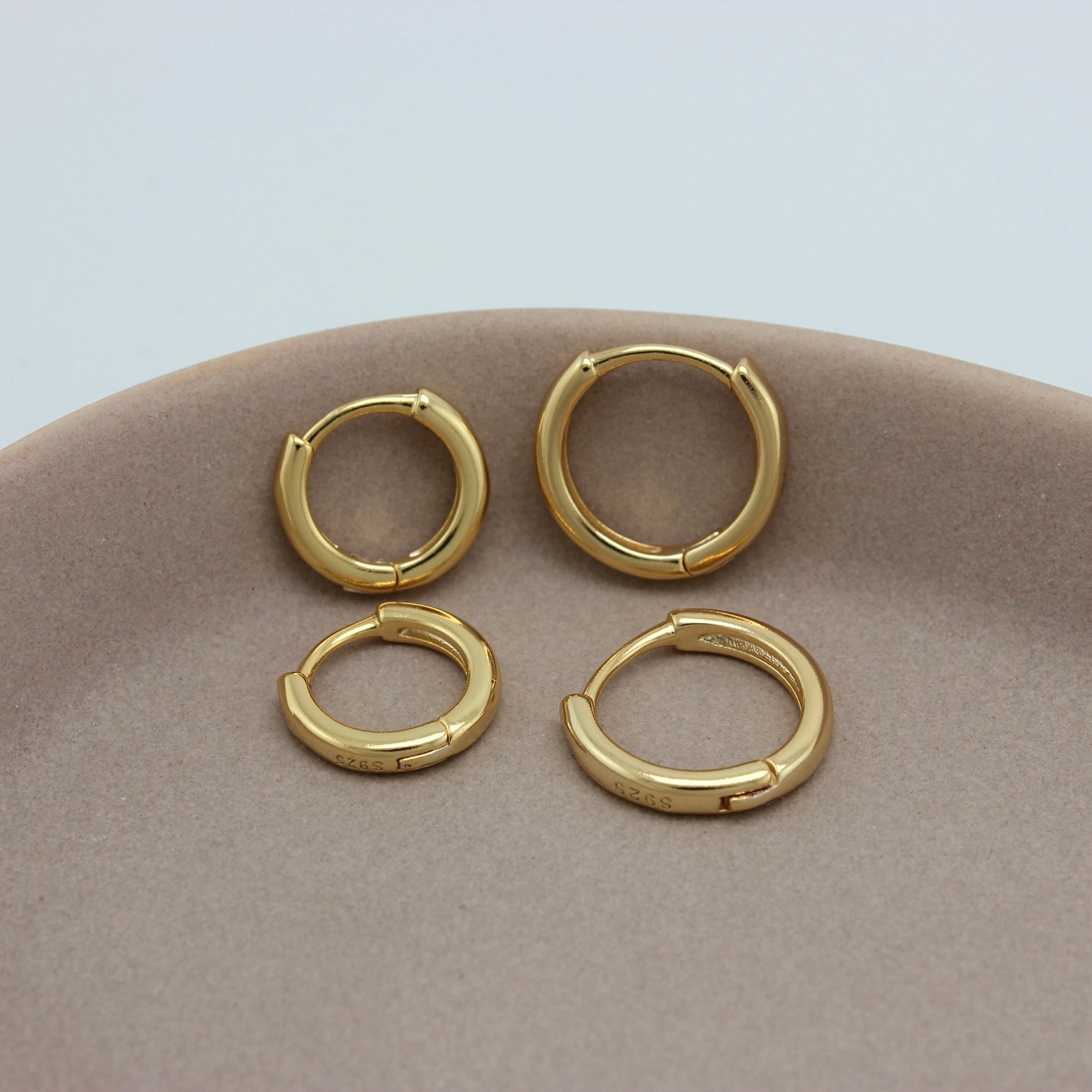 Kleine gouden hoops in twee formaten op een schaaltje