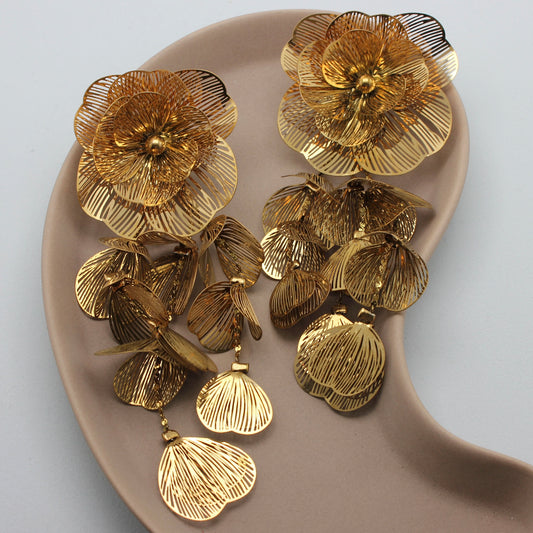 Feestelijke gouden oorbel met hangende bloemen en blaadjes vanuit een bovenaanzicht